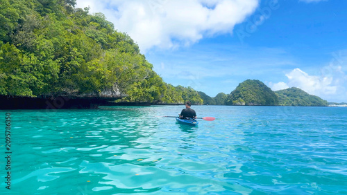 Фотография Man Kayaking Through Turquoise Waters Near Lush Tropical Rock Islands
