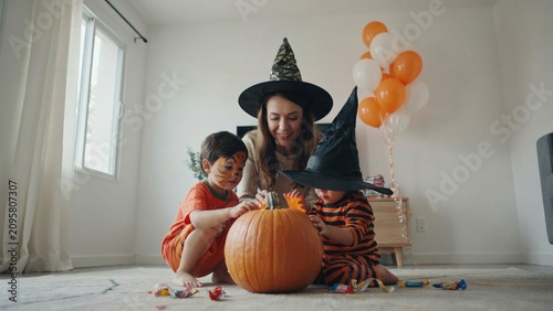 Family halloween fun mother and sons carving a pumpkin indoors
