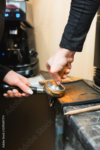 Canvas Print Barista hand holding a tamper and pressing coffee in a portafilter