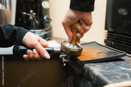 Cuadro en lienzo Detailed shot of a barista hand tamping ground coffee in a portafilter