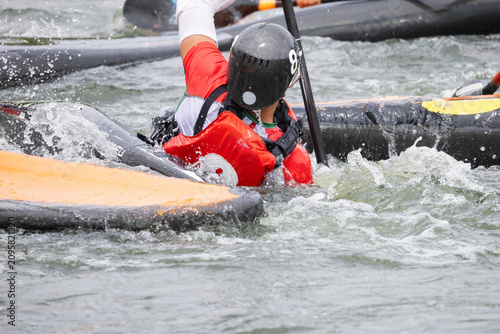 Принти на полотні Athlete in red kayak maneuvers through water during canoe polo match, with other