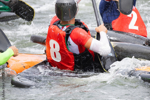 Принти на полотні Canoe polo players in colorful jerseys maneuvering their kayaks on a river, with
