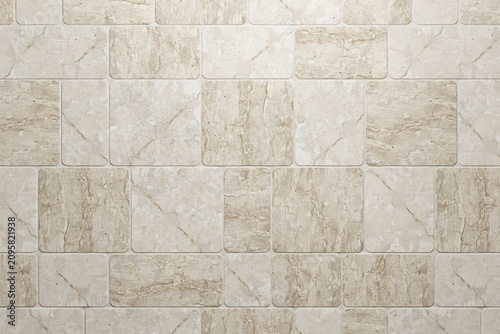 Close up view of a wall surface covered with rectangular beige marble tiles featuring natural veining patterns and smooth polished stone texture