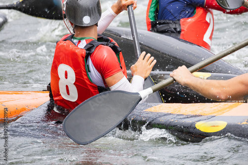 Canvas Print Canoe polo players in colorful jerseys maneuvering their kayaks on a river, with