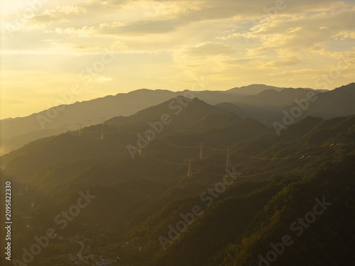 The sun sets over the green mountain ranges of the rural countryside in China as light shines across the rolling hills and the valley below