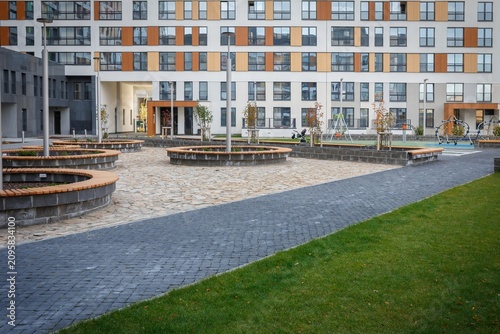 Courtyard plaza with paved pathway and round wooden benches near apartment buildings