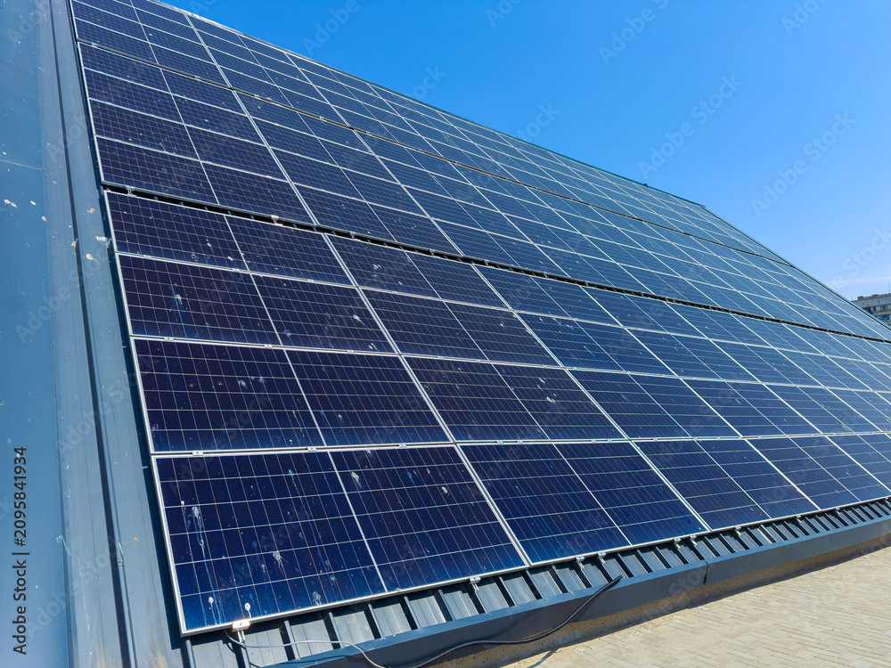 Obraz premium Solar panels installed on a roof at a location with clear blue skies during the daytime showing renewable energy use for power generation