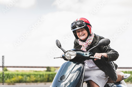 Active senior lady riding motor scooter on the road