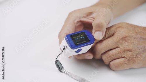 Close up of a caregiver placing a pulse oximeter on a senior finger to measure blood oxygen saturation and pulse rate, representing home healthcare, elderly care, medical monitoring, and wellness.