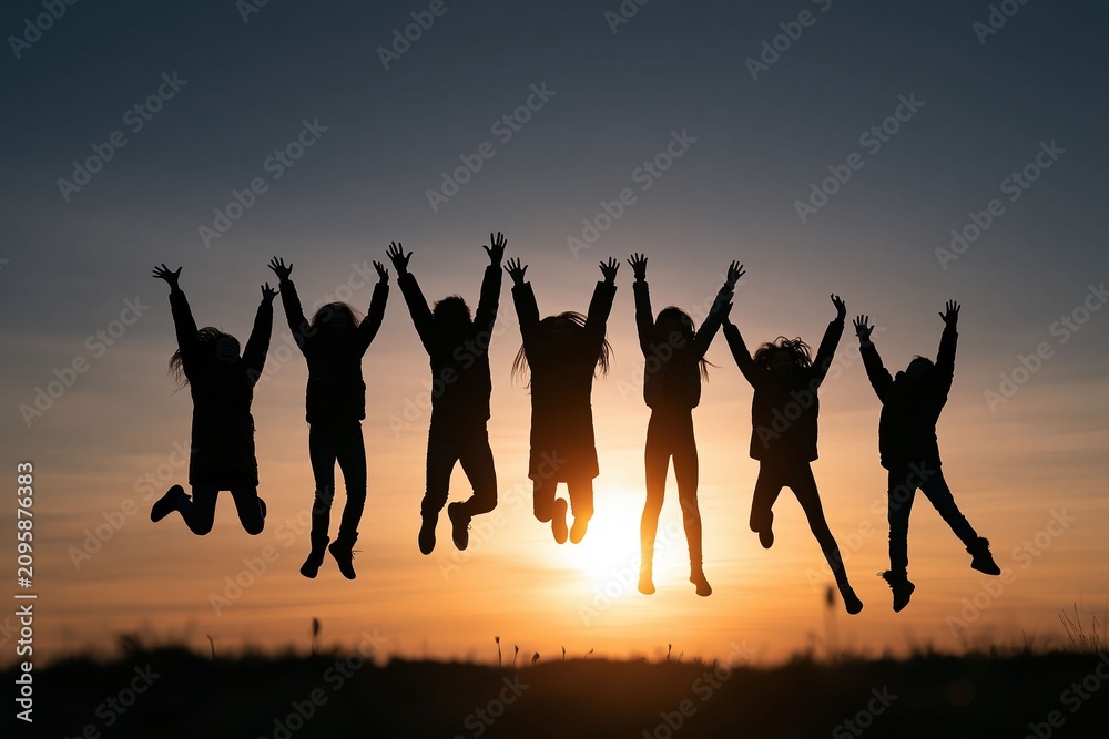 Fototapeta premium Youth Friendship Freedom, Friends jump against a glowing sunset sky expressing freedom, happiness, and the pure joy of friendship.