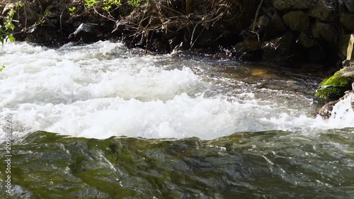 Close-up video of a turbulent mountain river with clear water, from behind along the current, and slightly above, in real time with sound. Soothing nature footage, 120 fps, Full HD