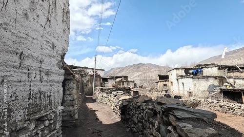 Dolly in stone walled lane through traditional mud brick village, Purang, Nepal