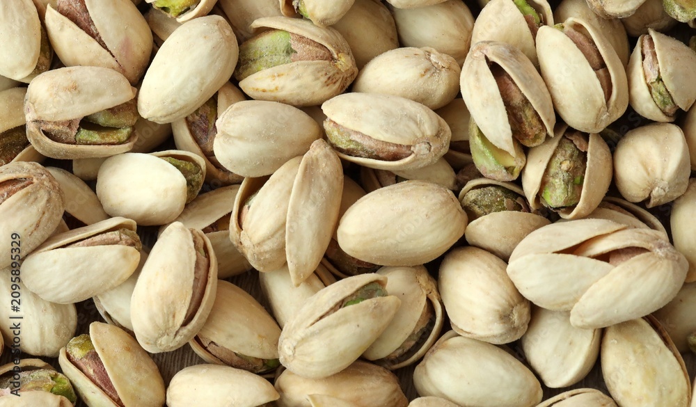 Fototapeta premium A photo of a pile of pistachios, with the majority still in their shells. Big amount of pistachios