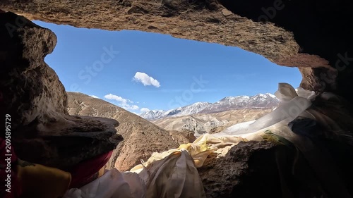 revealing view through Cave opening khata scarves snow peaks Jhong Chhoser cave Upper Mustang Nepal