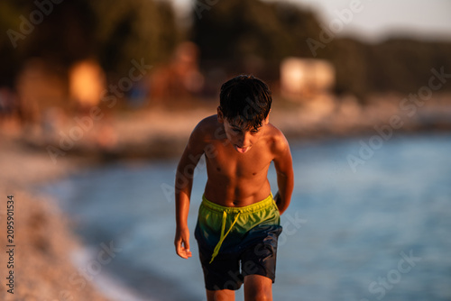 Φωτογραφία Young boy exiting ocean water at sunset beach