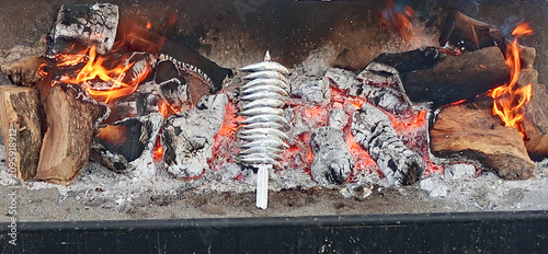 Фотография Skewer of sardines on a barbecue or charcoal grill