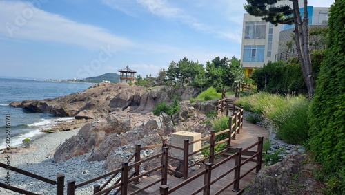 wooden boardwalk trail along rocky coastline with korean pavilion and pebble beach
