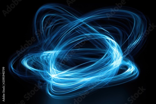 Blue light trails swirling in orbital motion on black background with sharp focus for technology branding