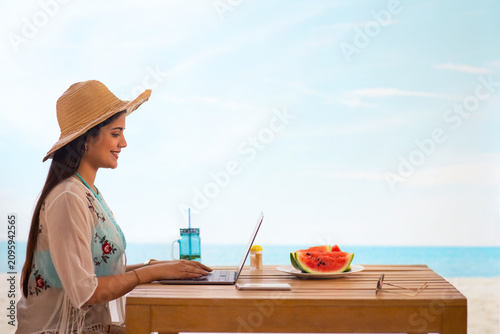 Woman using laptop while sitting at beach