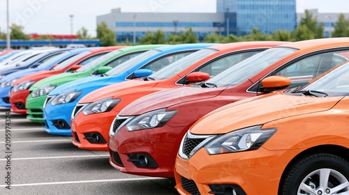 Row of colorful new sedans lined up in a dealership lot for sale