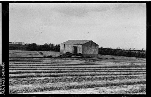 Black and White Analog Rural Landscape with Furrowed Field and Small Farm Building