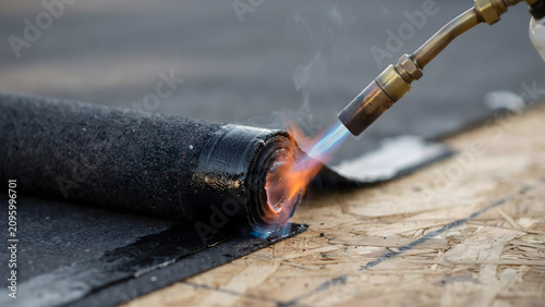 Applying bituminous waterproofing membrane with a gas torch on a roof