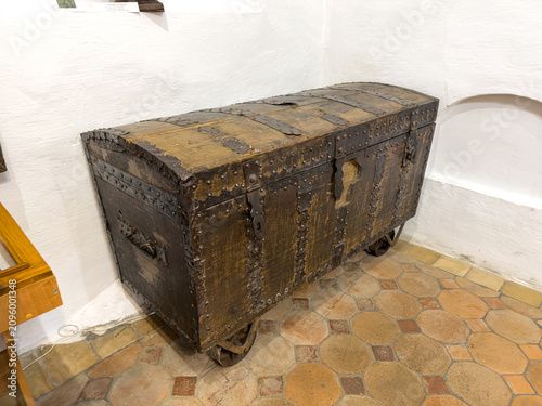 Картината върху платно Vintage wooden chest with metal reinforcements, mounted on wheels, featuring a d