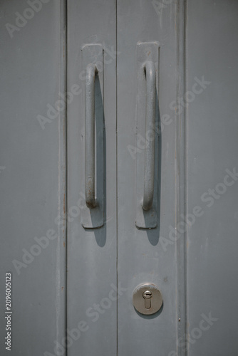 Obraz na płótnie Close up detail of two long metal pull handles and a keyhole cylinder lock on a grey painted door