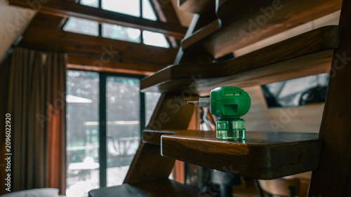 Fotografía Green electric mosquito repellent device plugged into a wooden staircase