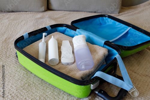 suitcase with towel electric toothbrush oral irrigator and cream inside showing travel preparation and personal care essentials concept of tourism wellness and lifestyle