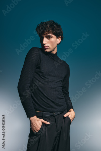 Handsome young man showcases stylish elegance in a modern, artistic setting.