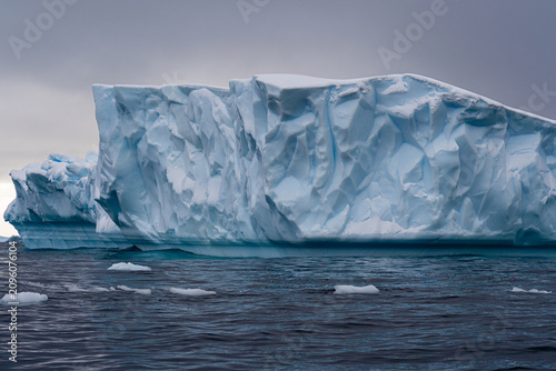 Large iceberg floats in dark water with grey skies above. Antarctic expedition. Antarctic Peninsula. Zodiac landing