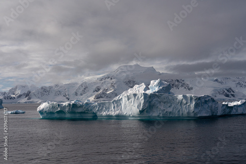 Massive Iceberg in the Ocean with Antarctic Mountains in the Background. Zodiac Landing During an Antarctic Expedition