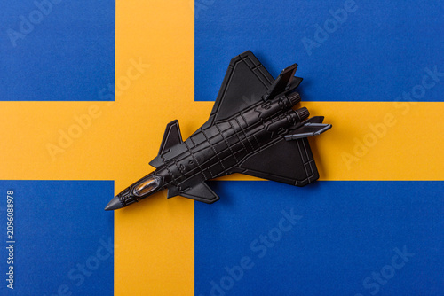 Obraz na plátně A fighter jet against the Swedish flag as a conceptual background representing d