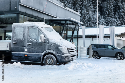 Foto Frost-covered delivery truck stands parked outside industrial building after heavy snowfall