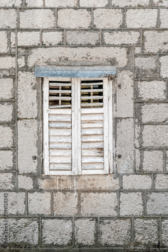 Vintage window with aged white wooden shutters on a traditional stone building facade. Authentic Mediterranean architecture on Njegoseva street in Cetinje, Montenegro, Europe