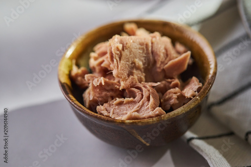 Close-up of canned tuna fish chunks in a brown ceramic bowl. Healthy protein ingredient for salads, sandwiches, and Mediterranean dishes.