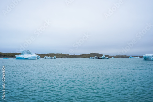 Foto Glacial icebergs floating in calm Arctic waters under an overcast sky,Jokulsarlo