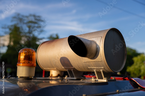 Fotografía Exhaust pipe silencer with orange flashing emergency beacon light installed on heavy machinery roof against blue sky background