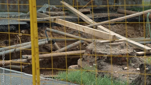 construction site where excavation is taking place. Wooden barricades and pipes are present, indicating active construction