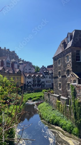 Scenic view of Dean Village along the Water of Leith in Edinburgh, historic stone houses reflected in the river, peaceful riverside landscape, charming Scottish heritage, picturesque neighborhood