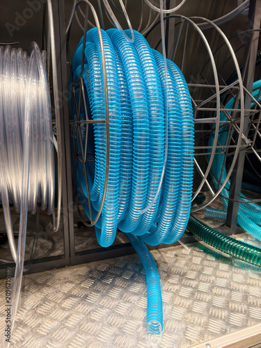 Fotografía Light blue corrugated hose and thin transparent hose rolled into compact coils a