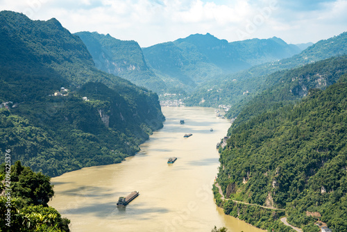 Cargo ships travel along the Yangtze River through the scenic Three Gorges Reservoir near Yichang in China on a bright sunny day