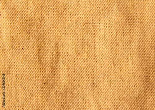 Close up light brown or beige cotton linen canvas texture with woven details. Natural coarse texture for design fabric background. Rough khaki crumpled hessian burlap background.