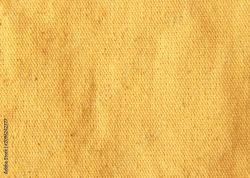 Close up golden bright yellow cotton linen canvas texture with woven details. Natural coarse texture for design fabric background. Rough crumpled hessian burlap background.