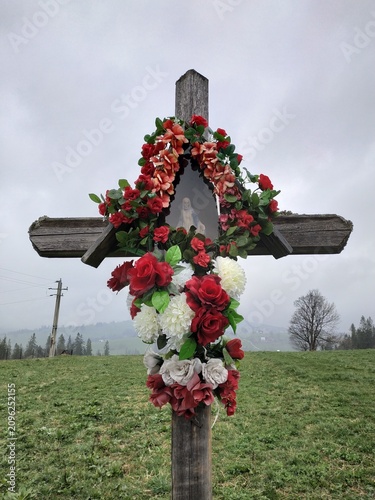 Rustic Wooden Cross Adorned with Vibrant Floral Wreath in Misty Zakopane Landscape