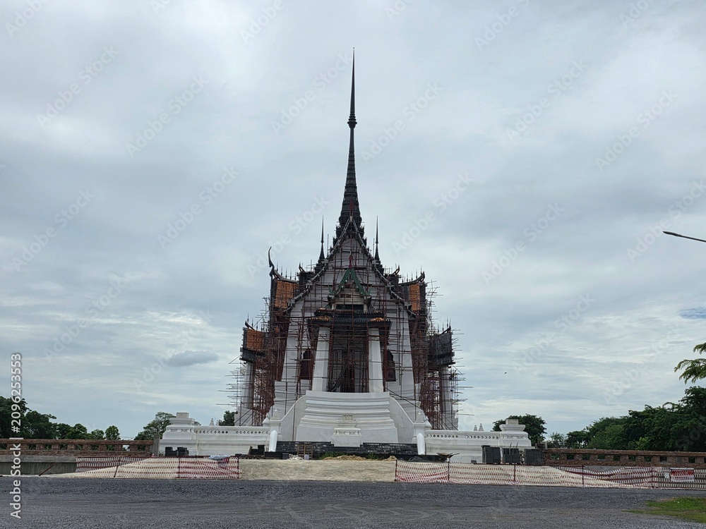 Obraz premium Grand Temple Structure Under Construction: An impressive, intricately designed temple structure, adorned with traditional spires and ornate details, stands tall against a cloudy sky.