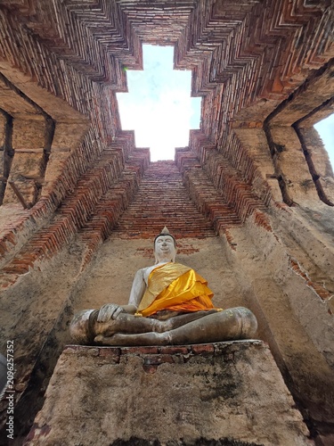 Buddha Statue in Ancient Temple: A serene Buddha statue sits in contemplation within the weathered brick structure of an ancient temple.