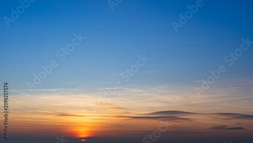 A vivid sunset sky transitions from deep blue to warm orange near the horizon, with wispy clouds