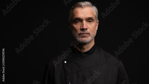 Man chef portrait, arms crossed isolated on black background. Culinary service, professional male cook and smile
